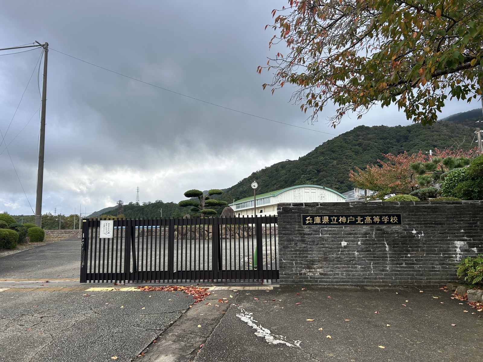 兵庫県立神戸北高等学校の校門と、奥の体育館と山並み